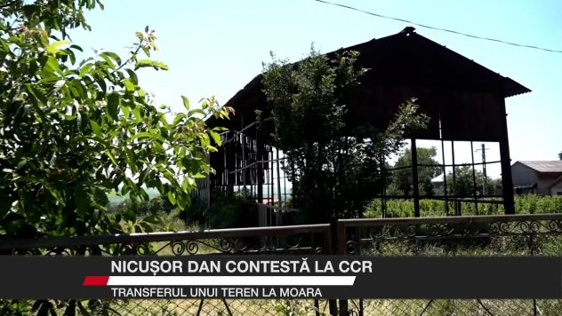 O construcție metalică abandonată și vegetație deasă într-un teren împrejmuit din comuna Moara.