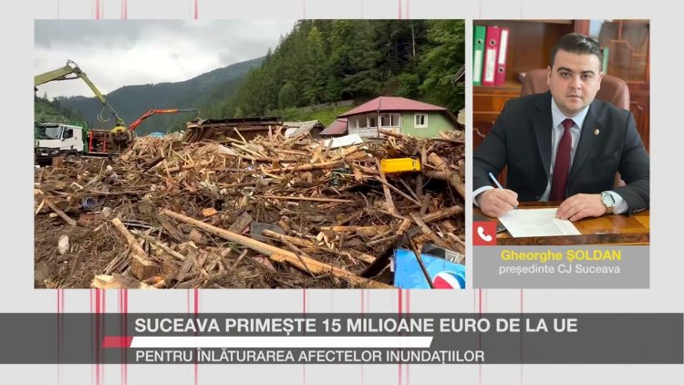 Gheorghe Șoldan, președintele CJ Suceava, apare într-un cadru video alături de o imagine a daunelor provocate de inundații, cu bușteni și resturi adunate pe un drum.